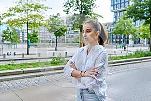 Serious confident teenage girl looking forward, outdoor on city street