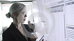 Serious content female boss checking data in tablet