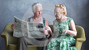 Serious conversation of elderly couple. wife is watching TV, husband reads newspaper