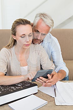 Serious couple calculating their bills at the couch