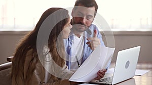 Serious couple holding papers reading domestic bills sitting with laptop