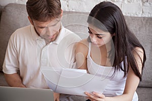 Serious couple reading mail analyzing finances at home