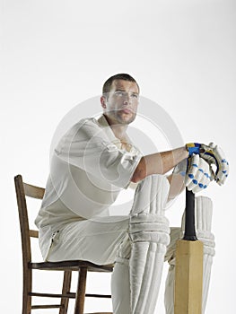 Serious Cricket Player Sitting With Bat