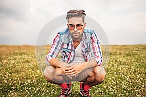 Serious crouched casual man in a field of grass