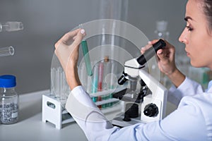 Serious cute researcher keeping the test glass and observe it.