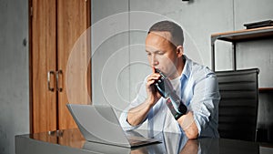 Serious cyborg man programmer with artificial limb prothesis looks around sitting at table