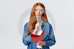 Serious and determined bossy cute redhead girl with notebook, holding pen, smirk thoughtful and look away as thinking