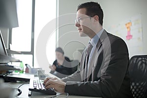 Serious devoted business man work in office on computer. Real economist business people, not models. Bank employees discussing