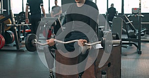 serious disabled man sitting on fitness box holding barbell