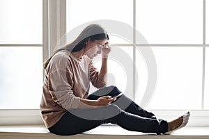 Serious and distressed woman using a smartphone photo