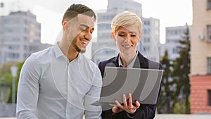 Serious diverse multiracial couple colleagues arabic hispanic man and caucasian woman standing near business center at