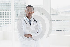 Serious doctor with arms crossed in a medical office