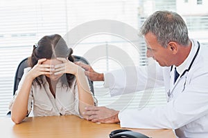 Serious doctor comforting his patient after telling her diagnosis