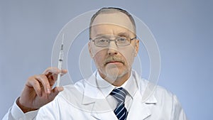 Serious doctor holding syringe, ready to make vaccine injection, flu epidemic