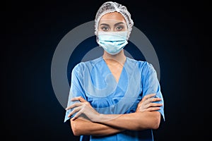 Serious doctor in medical mask and cap looking camera