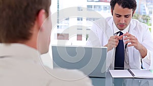 Serious doctor talking to his patient while sitting