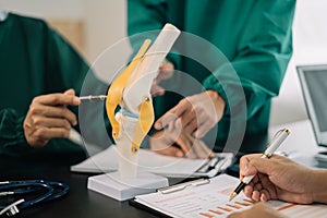 serious doctors team are analyzing fracture knee model showing the process of osteoarthritis patients and knee arthroplasty