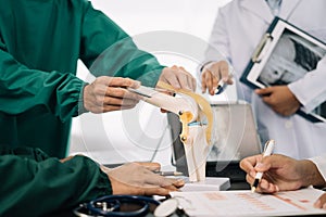 serious doctors team are analyzing fracture knee model showing the process of osteoarthritis patients and knee arthroplasty