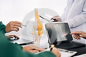 serious doctors team are analyzing fracture knee model showing the process of osteoarthritis patients and knee arthroplasty