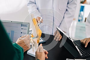 serious doctors team are analyzing fracture knee model showing the process of osteoarthritis patients and knee arthroplasty