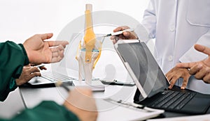 serious doctors team are analyzing fracture knee model showing the process of osteoarthritis patients and knee arthroplasty
