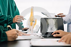 serious doctors team are analyzing fracture knee model showing the process of osteoarthritis patients and knee arthroplasty