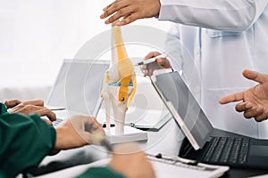 serious doctors team are analyzing fracture knee model showing the process of osteoarthritis patients and knee arthroplasty