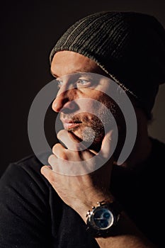 Serious dramatic man looking away while standing against black studio background