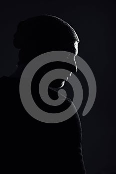 Serious dramatic man looking away while standing against black studio background