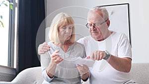 Serious elderly husband and wife review utility bills. Worried elderly couple.