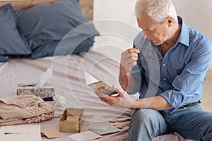 Serious elderly man reading an old postcard