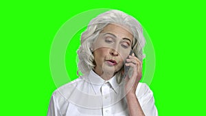 Serious elderly woman talking on phone.