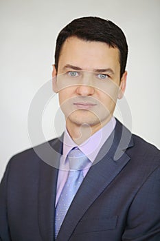 Serious elegance brunet man in suit poses next to photo