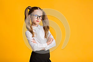 Serious Elementary School Girl Posing Crossing Hands Over Yellow Background