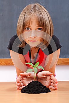 Serious elementary schoolgirl protecting plant