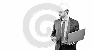 Serious engineer man in hardhat and suit use laptop computer for constructing, engineering