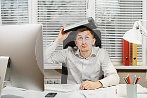 Serious and engrossed business man in shirt sitting at the desk, working at computer with modern monitor. Manager or worker.