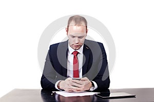 Serious European businessman in red tie at the table sends SMS.