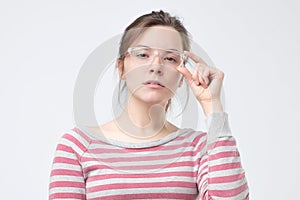 Serious european woman wearing big elegant glasses having thoughtful expression.