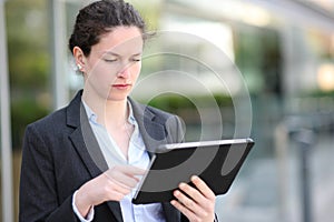 Serious executive working using tablet in the street