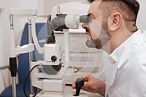 Serious experienced doctor working in the eye lab