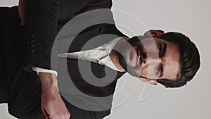 Serious expressive angry latin businessman in a tuxedo crossing his arms on his chest. Vertical medium studio shot on