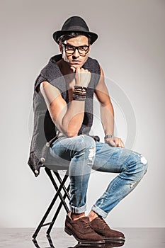 Serious fashion man sitting on chair is thinking