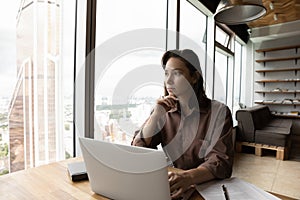 Serious female business leader, entrepreneur looking out of window