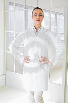 Serious female doctor with hands on hips in hospital