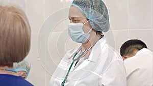 Serious female doctor in mask standing in a surgical room