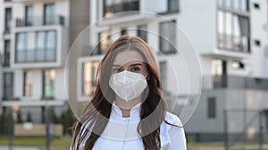 Serious female doctor outdoor portrait with face mask stands and looking at the camera