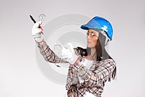 Serious female electrician repairing light with a light bulb in her hands. White background