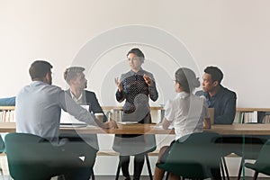 Serious female indian manager talk at group meeting behind glass