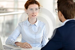 Serious female insurance broker talking consulting male client at meeting